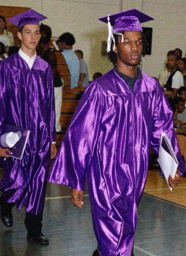 Young Emmanuel Banks walking in purple cap and gown at graduation