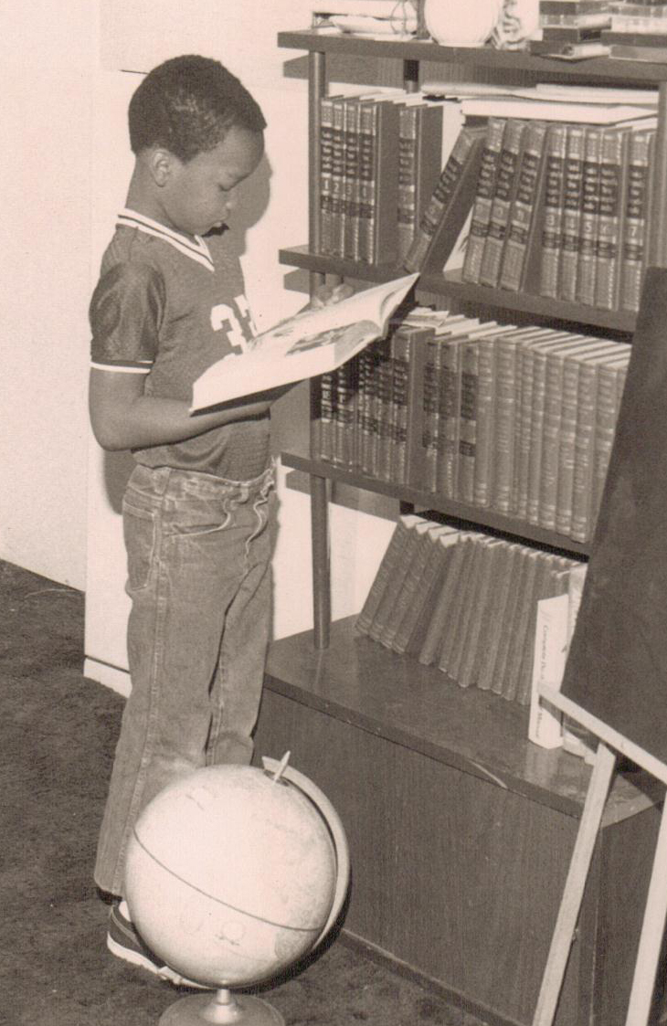 Young Emmanuel Banks reading a book as a child